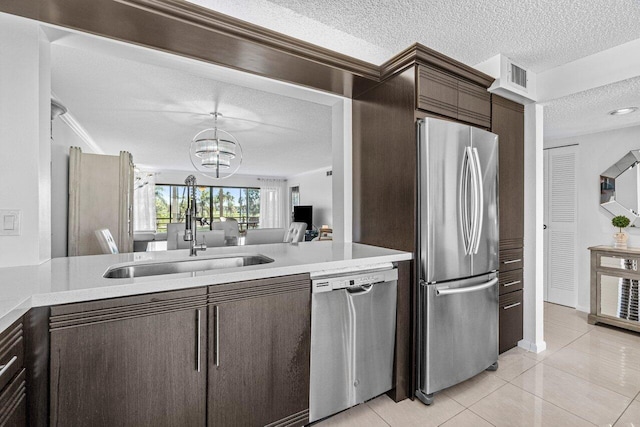 kitchen featuring dark brown cabinetry, sink, a textured ceiling, light tile patterned floors, and appliances with stainless steel finishes