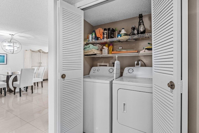 washroom with light tile patterned flooring, separate washer and dryer, a textured ceiling, and a notable chandelier