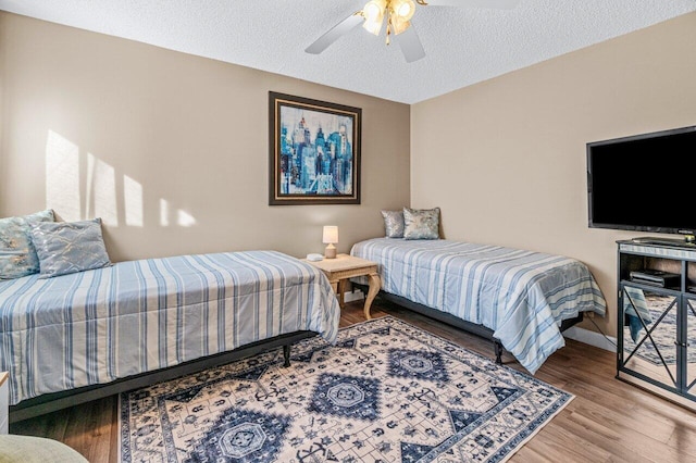 bedroom with ceiling fan, wood-type flooring, and a textured ceiling