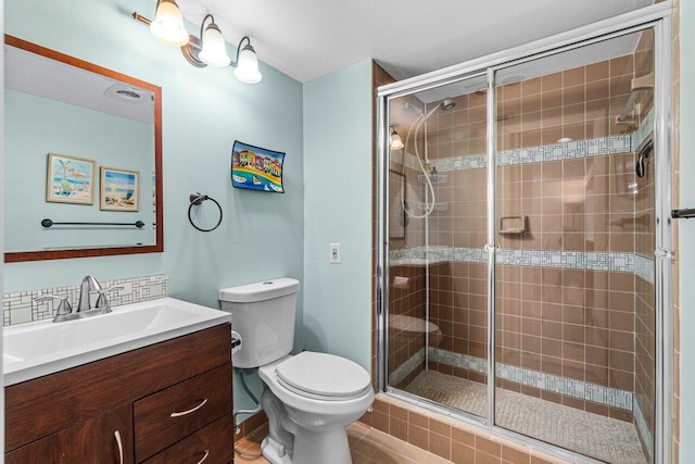 bathroom featuring a shower with door, vanity, and toilet