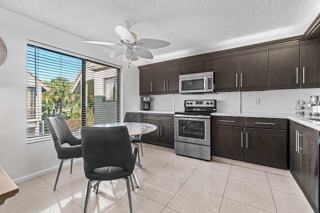 kitchen featuring a textured ceiling, dark brown cabinets, light tile patterned floors, appliances with stainless steel finishes, and ceiling fan