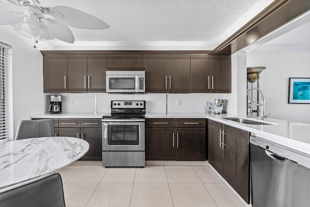 kitchen featuring sink, a textured ceiling, light tile patterned floors, appliances with stainless steel finishes, and ceiling fan