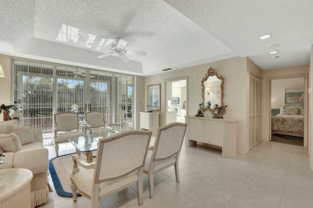 interior space featuring ceiling fan, a tray ceiling, and a textured ceiling