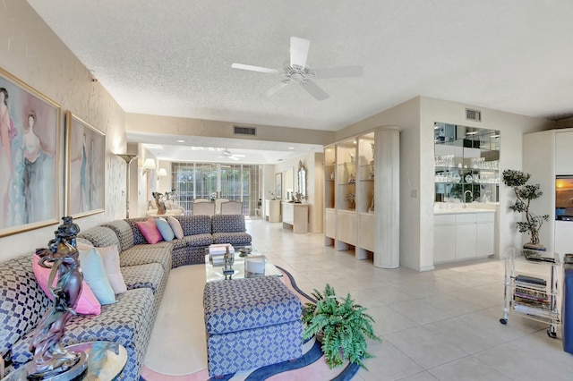 tiled living room with ceiling fan and a textured ceiling