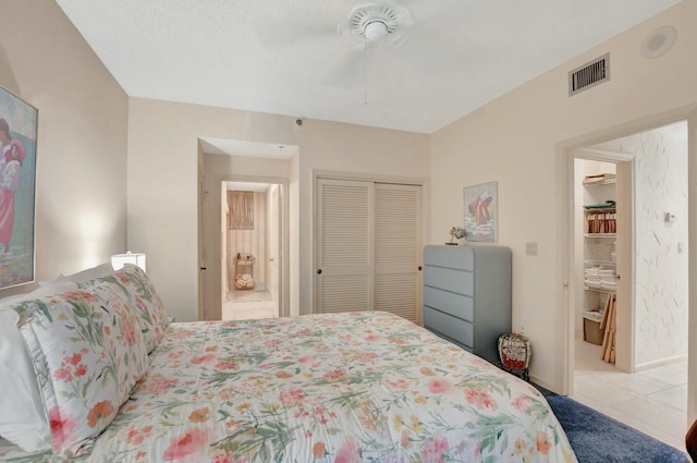 bedroom with ceiling fan, connected bathroom, a closet, and light tile patterned floors