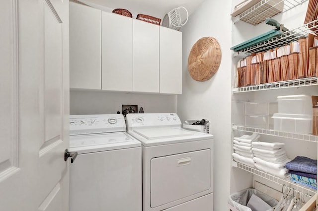 clothes washing area with cabinets and washing machine and clothes dryer