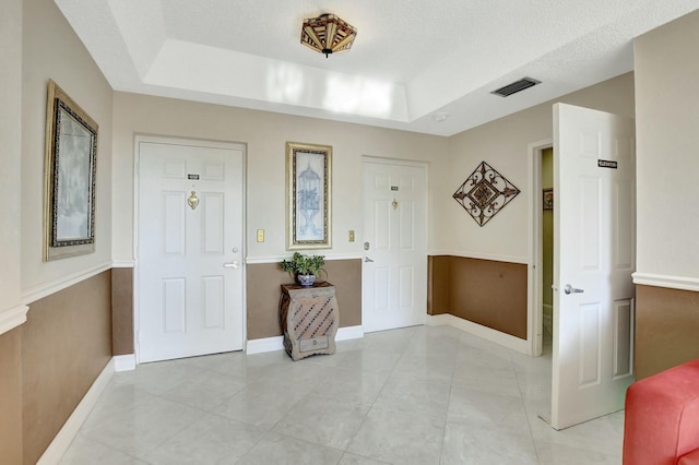 entrance foyer featuring a raised ceiling and a textured ceiling