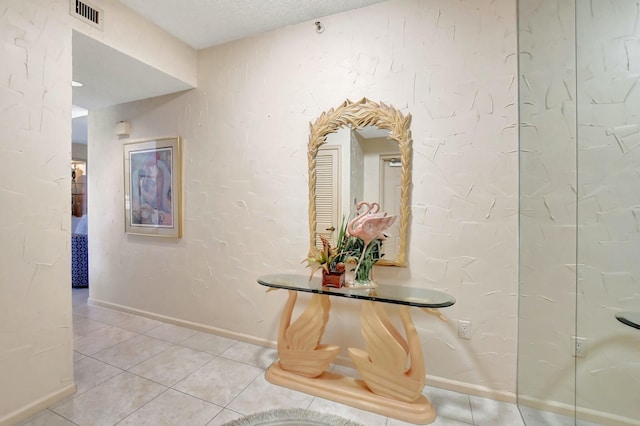 corridor featuring a textured ceiling and light tile patterned flooring