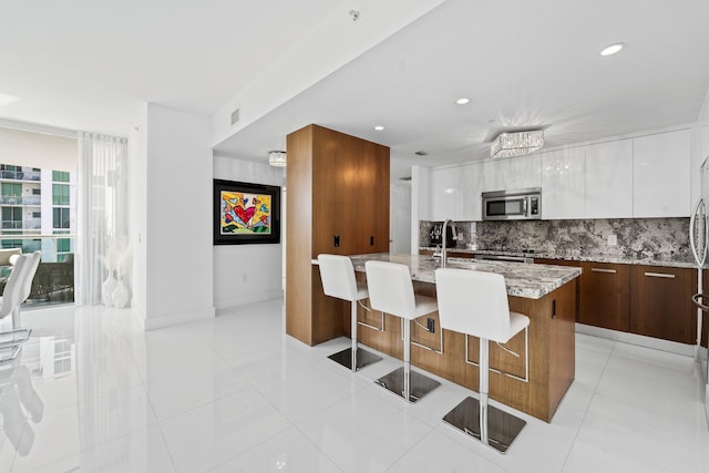 kitchen with appliances with stainless steel finishes, tasteful backsplash, white cabinetry, sink, and light stone counters