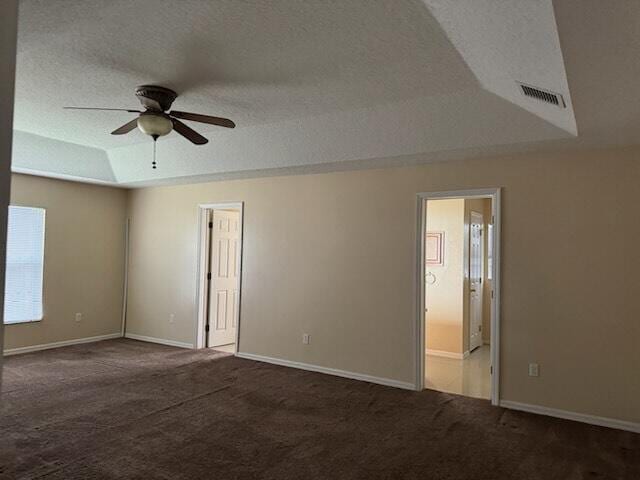 carpeted spare room featuring ceiling fan, lofted ceiling, a textured ceiling, and a tray ceiling