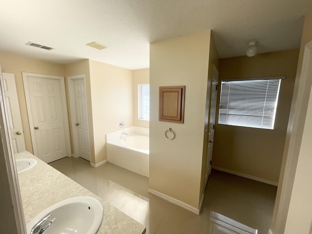 bathroom with vanity, a bath, and tile patterned floors