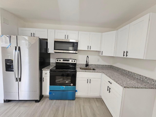 kitchen featuring white cabinetry, appliances with stainless steel finishes, sink, and light stone counters