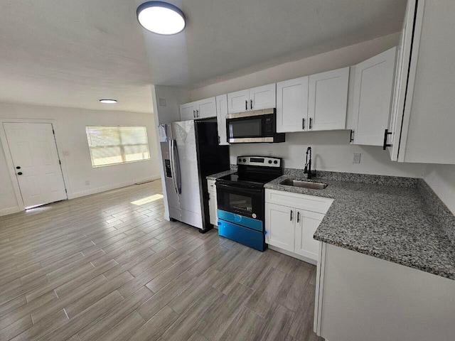 kitchen featuring white cabinetry, sink, dark stone counters, stainless steel appliances, and light hardwood / wood-style flooring