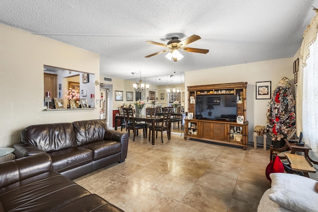 living room with light tile patterned flooring, ceiling fan with notable chandelier, and a textured ceiling