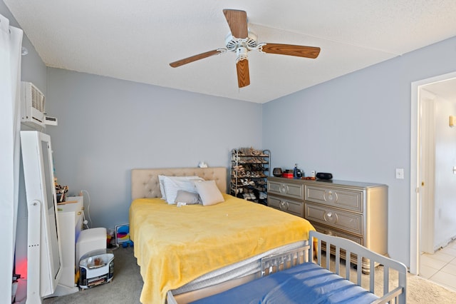 carpeted bedroom with a wall unit AC and ceiling fan