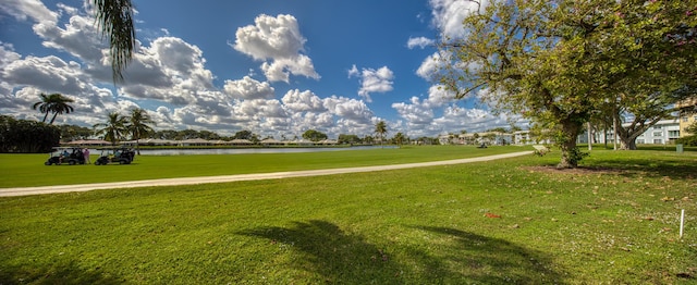 surrounding community with a water view and a yard