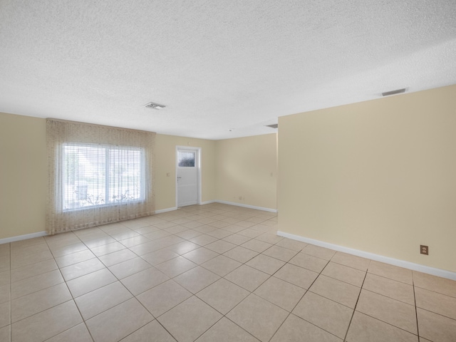 tiled empty room with a textured ceiling