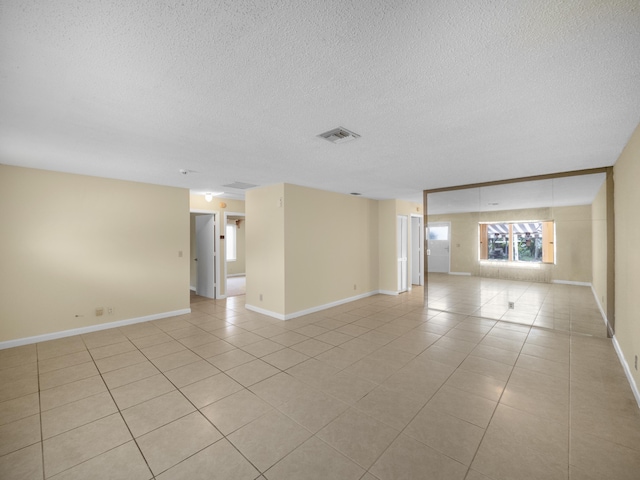 tiled empty room with a textured ceiling