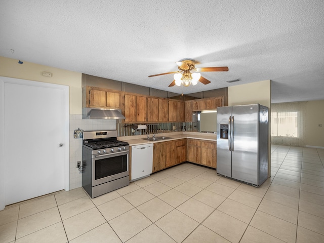 kitchen with sink, a textured ceiling, light tile patterned floors, appliances with stainless steel finishes, and ceiling fan