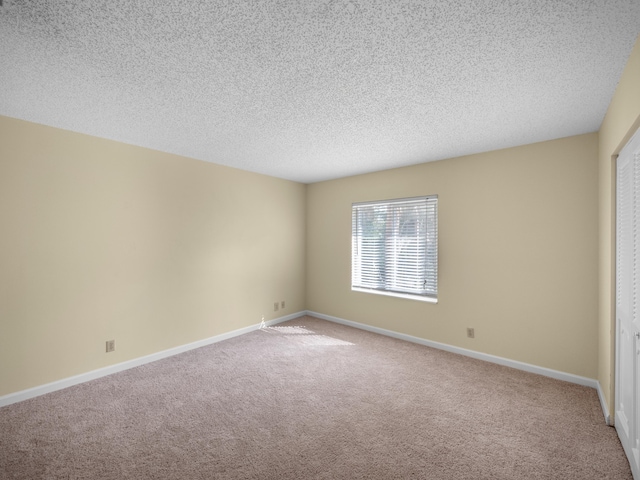 carpeted empty room featuring a textured ceiling