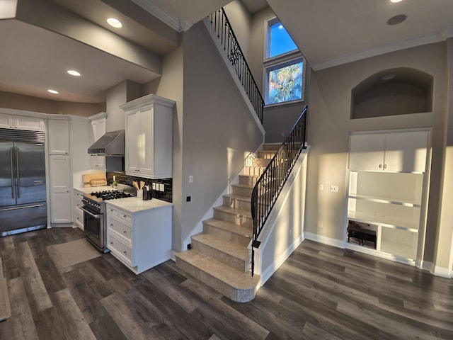 kitchen featuring high end appliances, white cabinetry, ornamental molding, and dark wood-type flooring