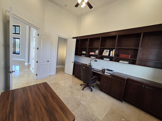 unfurnished office featuring crown molding, ceiling fan, and a high ceiling