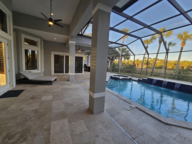 view of pool featuring ceiling fan, a patio, glass enclosure, pool water feature, and an in ground hot tub