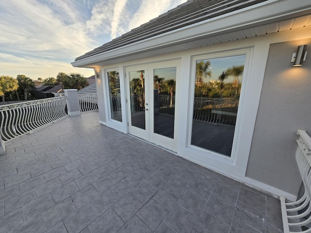 patio terrace at dusk featuring french doors and a balcony