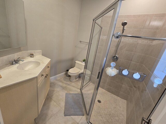 bathroom with vanity, a shower with shower door, tile patterned floors, and toilet