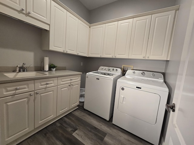 laundry area featuring dark hardwood / wood-style flooring, sink, washing machine and dryer, and cabinets