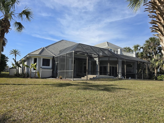 rear view of house with a yard and a lanai