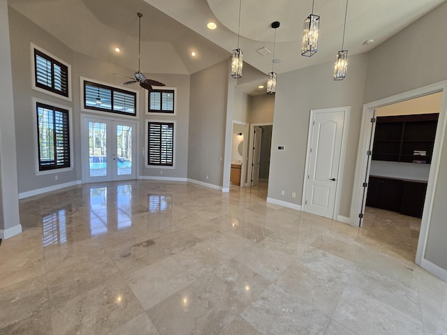 unfurnished room with french doors, ceiling fan, and a high ceiling