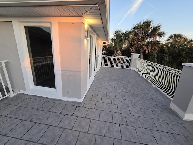 patio terrace at dusk featuring a balcony