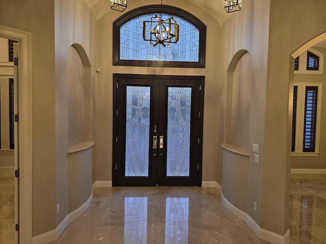 entrance foyer featuring french doors, a chandelier, and a high ceiling