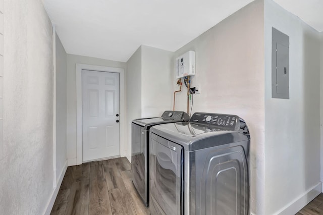 laundry area with washing machine and clothes dryer, wood-type flooring, and electric panel