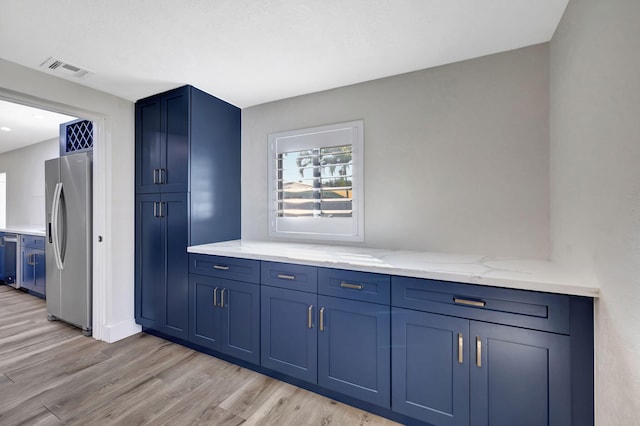 bar with blue cabinetry, light wood-type flooring, light stone countertops, and appliances with stainless steel finishes