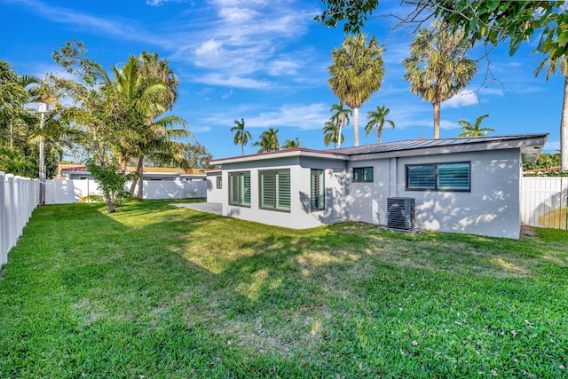 rear view of property featuring central air condition unit and a lawn