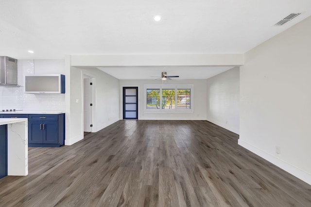 unfurnished living room featuring dark wood-type flooring and ceiling fan