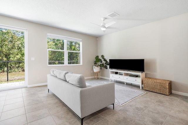 living room with ceiling fan, light tile patterned floors, and a textured ceiling