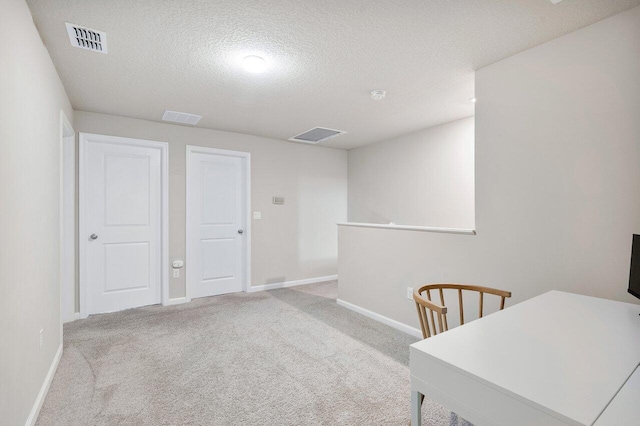 office space featuring light carpet and a textured ceiling