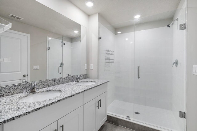 bathroom with vanity, a textured ceiling, and a shower with shower door