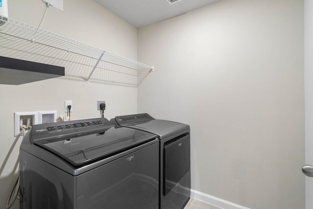 clothes washing area featuring washing machine and clothes dryer and tile patterned floors