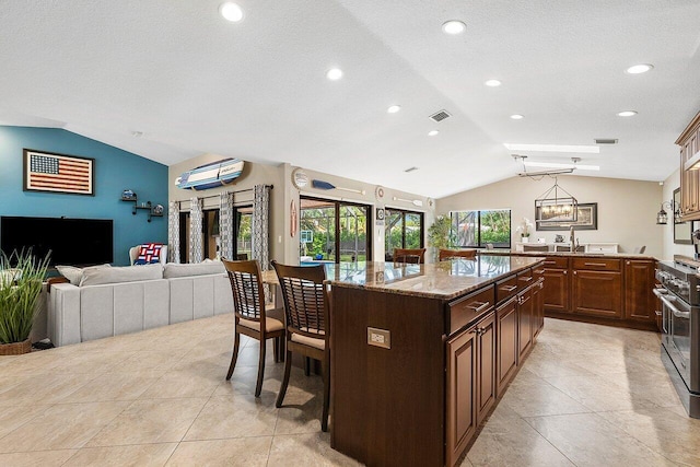 kitchen with visible vents, a kitchen island, a breakfast bar, vaulted ceiling, and double oven range