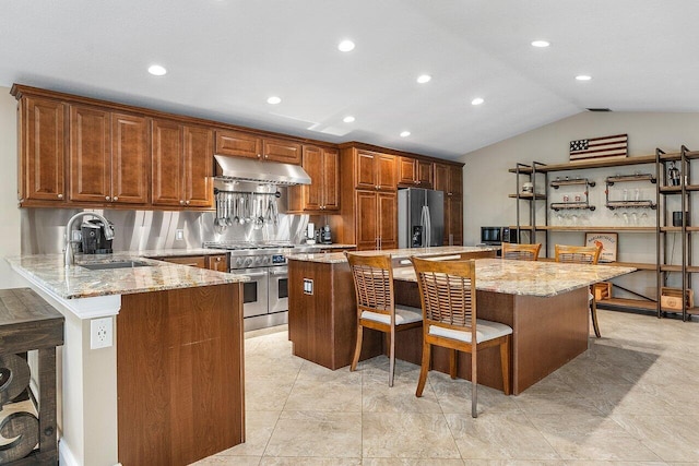 kitchen with light stone counters, a breakfast bar, appliances with stainless steel finishes, a sink, and under cabinet range hood