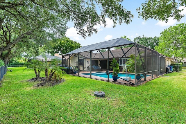 pool with glass enclosure, a yard, and fence