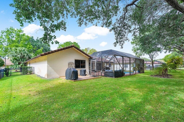 back of house featuring a lanai, a yard, fence, and stucco siding