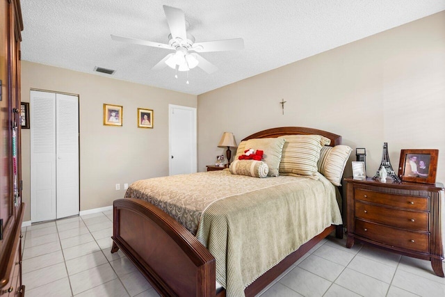 bedroom featuring light tile patterned floors, a closet, a textured ceiling, and ceiling fan