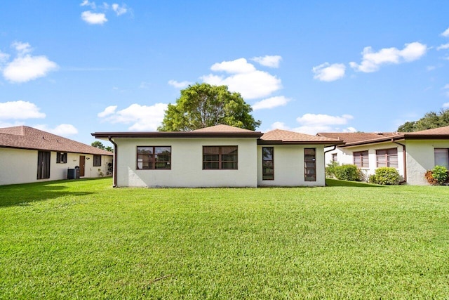 back of property featuring cooling unit and a lawn