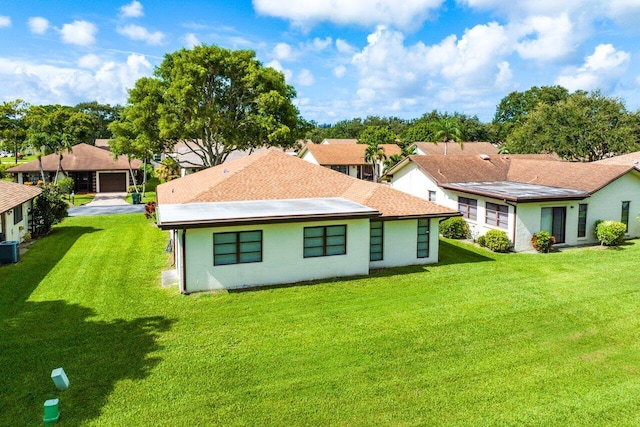 rear view of house with a garage, a lawn, and central air condition unit