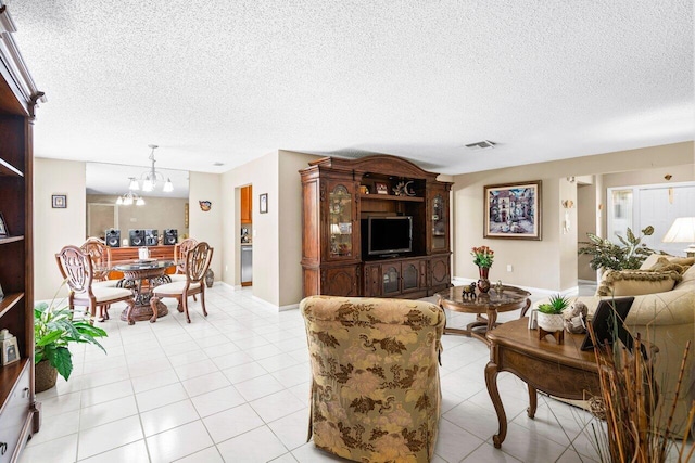 living room with light tile patterned floors, a notable chandelier, and a textured ceiling